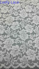 Tessuto di pizzo a tutta larghezza in bianco, decorato con delicati disegni floreali e bordi ricci lussuosamente